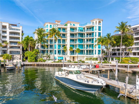Front view of a multi-story building with balconies facing a waterfront.