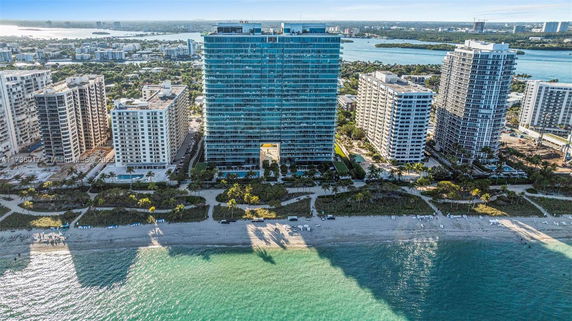 Aerial view of high-rise buildings along a beach with cityscape in the background.