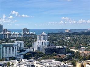 Wide-angle view of a urban area with several high-rise buildings and the ocean in the distance.