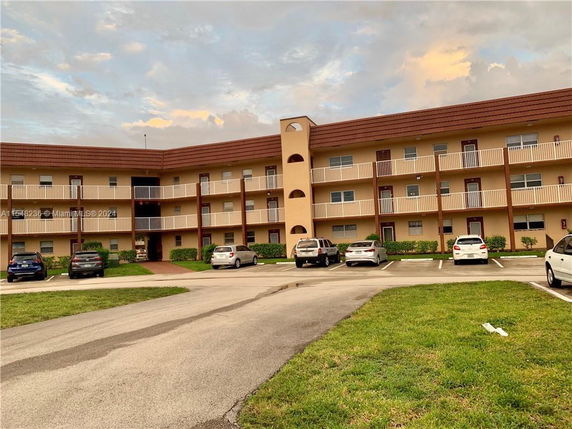 Front view of a three-story residential building with a parking area in front.