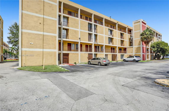 Front view of a multi-story residential building with parking area.