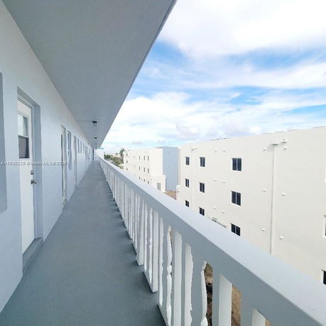 View of a building corridor with white walls and a view of adjacent buildings.