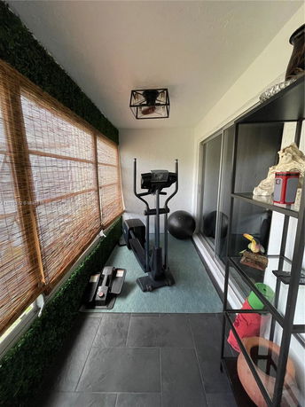 Indoor area with exercise equipment including an elliptical and yoga mat.