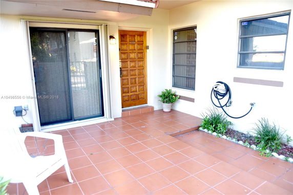 Front view of a house entrance with sliding glass door and wooden door.