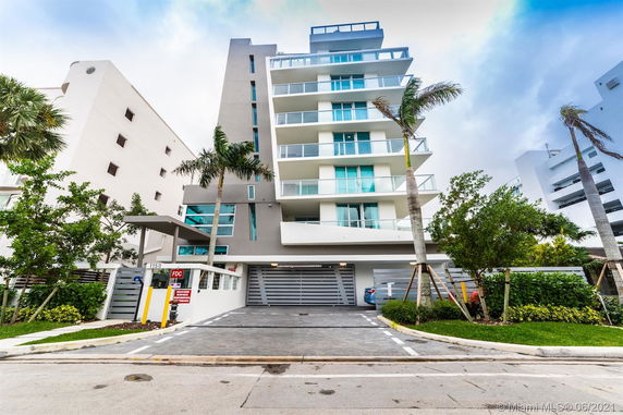 Front view of a modern multi-story building with balconies and a garage entrance.