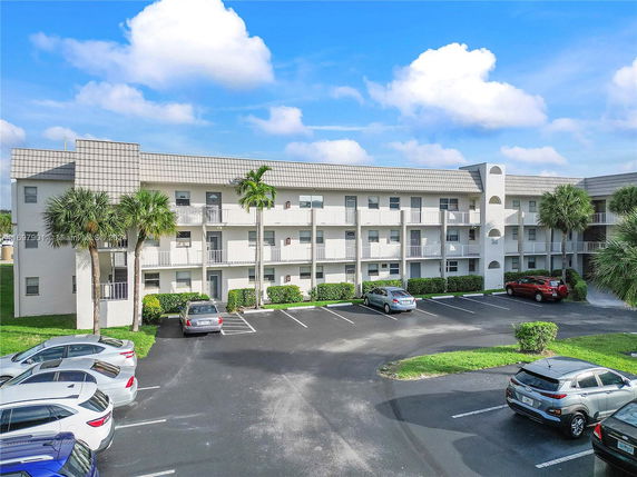Front view of a multi-story apartment building with parking area.