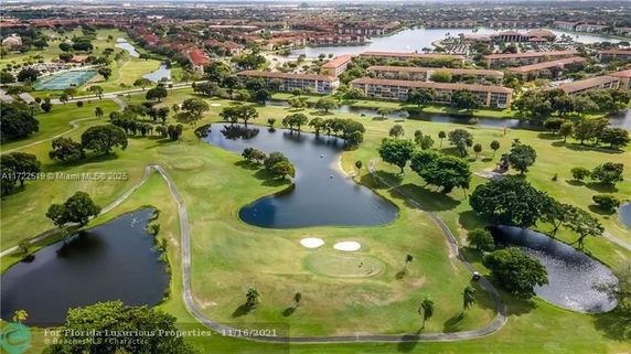 Aerial view of a golf course with ponds and surrounding buildings.
