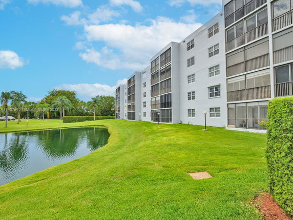 Side view of a multi-story residential building with screened balconies near a pond.