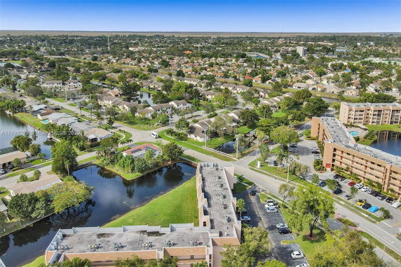 Panoramic view of a suburban area with houses and buildings surrounded by greenery and water bodies.