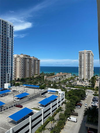 Panoramic view of several high-rise buildings near the ocean with blue sky.