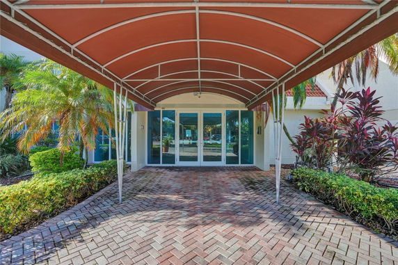 Front view of a building entrance with a red canopy and glass doors.