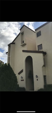 Front view of a multi-story house with arched entrance and sloped roof.