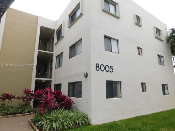 Front view of a multi-story building with external corridors and windows.