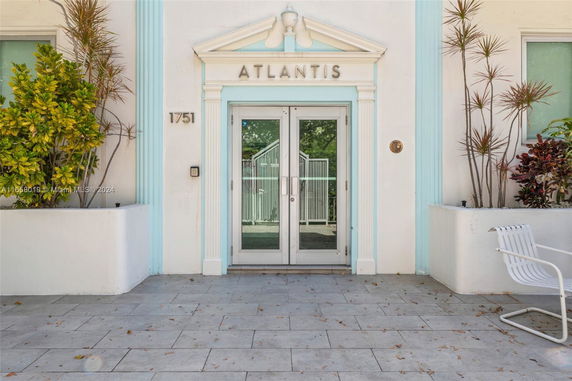 Entrance view of a building labeled Atlantis with a glass door.