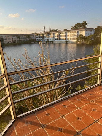 Panoramic view from a balcony overlooking a lake and apartment buildings.