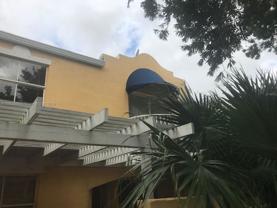Front view of a house with a blue awning and pergola.