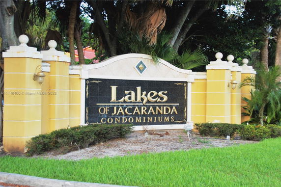 Sign for Lakes of Jacaranda Condominiums surrounded by landscaping.
