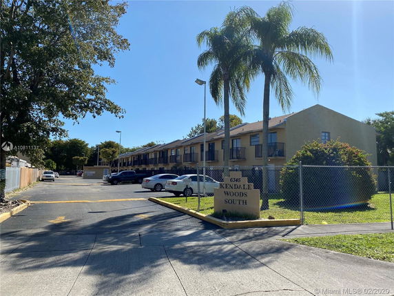Front view of a two-story residential building with a parking area.