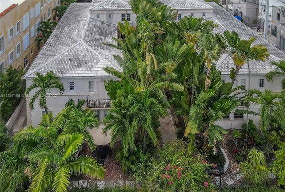 Front view of a large residential building with a gable roof surrounded by palm trees.