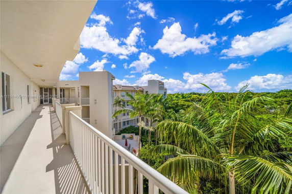 Panoramic view from a balcony overlooking a building and lush greenery.