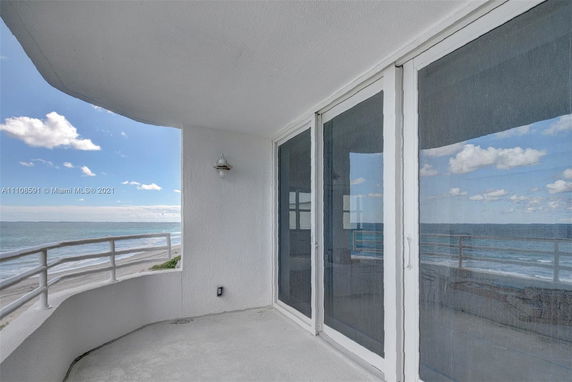 View from a balcony with glass doors, overlooking the ocean.
