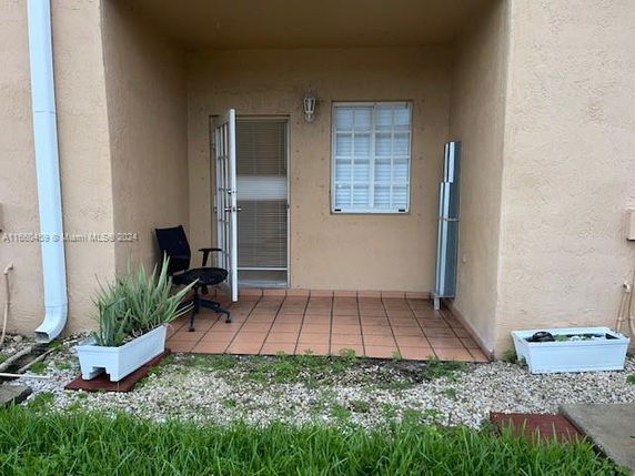 Front view of a house with a small covered patio area and potted plants.