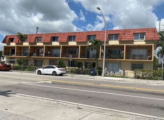 Front view of a two-story building with balconies and a red roof.