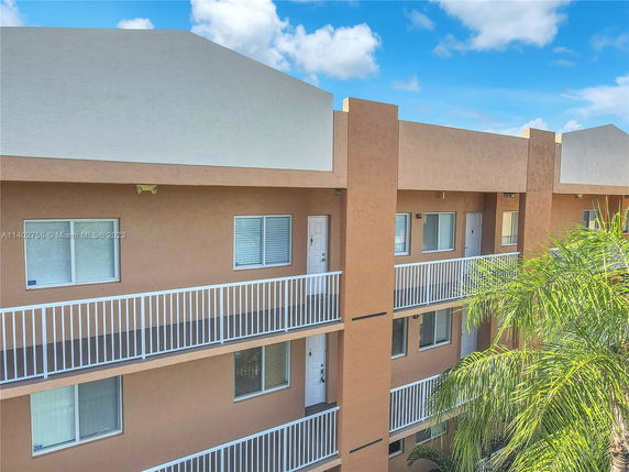 Front view of a multi-story building with balconies and white railings.