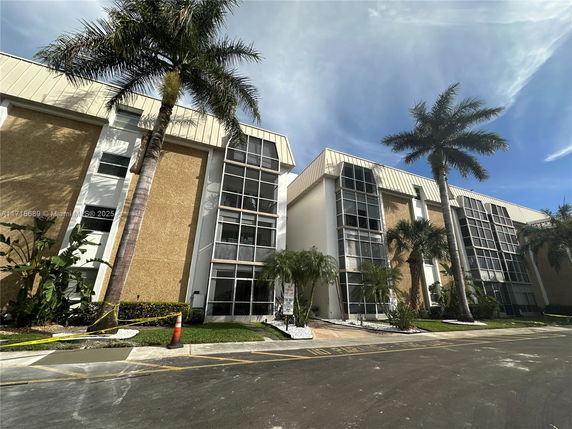 Front view of a multi-story building with large windows and a sloped roof.