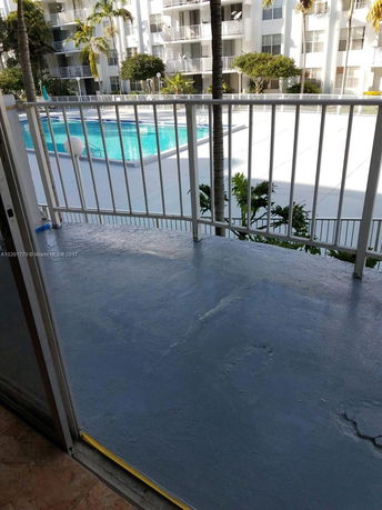 View from a balcony overlooking a swimming pool and apartment building.