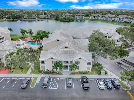 Aerial view of residential buildings near a lake with parking area in the foreground.