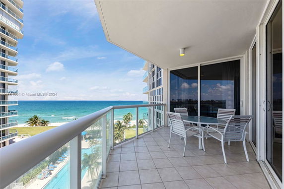 Balcony view overlooking the ocean with beach and pool visible.