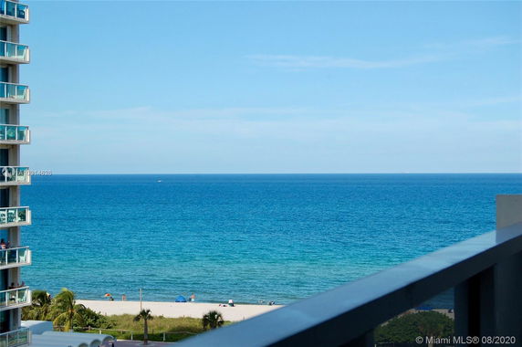 Panoramic view of the ocean from a building balcony, with part of the building visible on the left.