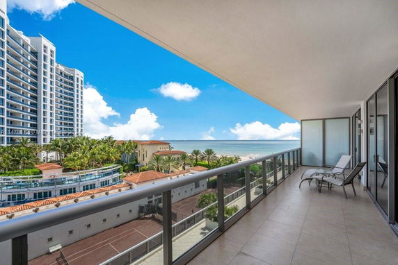 Wide-angle view from a balcony overlooking the ocean and nearby buildings.