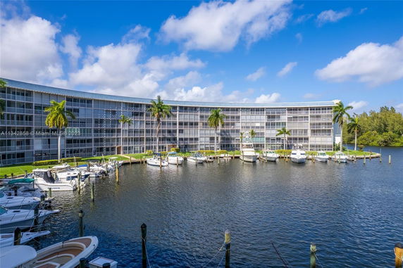 Curved multi-story building with balconies overlooking a marina with docked boats.