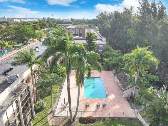 Elevated view of a residential area with a swimming pool surrounded by trees.