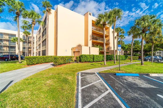 Front view of a multi-story building with balconies and palm trees.