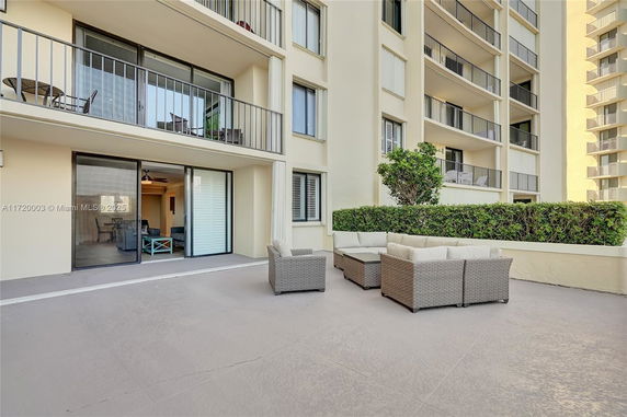 Outdoor patio area with seating in front of a modern multi-story building with balconies.