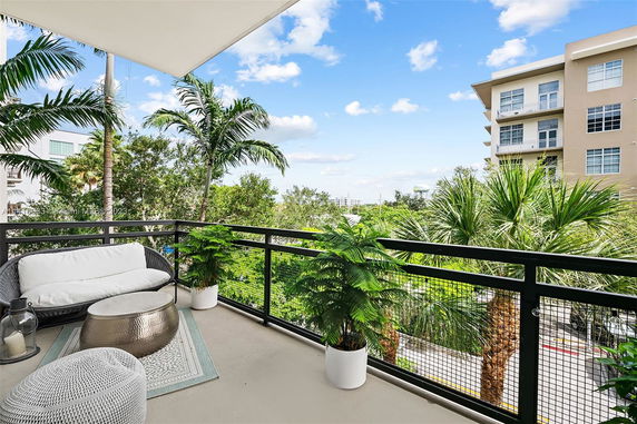 View from a balcony overlooking surrounding trees and a multi-story building.