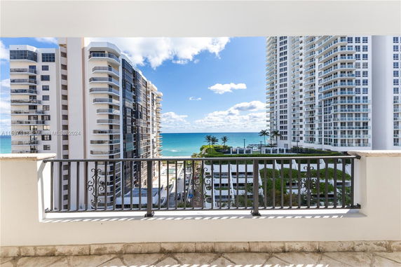 Panoramic view from a building balcony overlooking high-rise buildings and the ocean.
