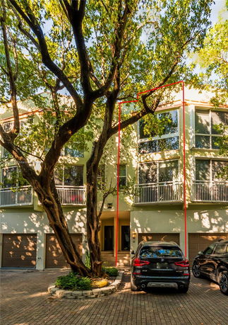 Front view of a multi-story townhouse with garages and balconies.