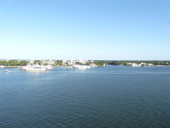 View of waterfront buildings and yachts across a body of water.