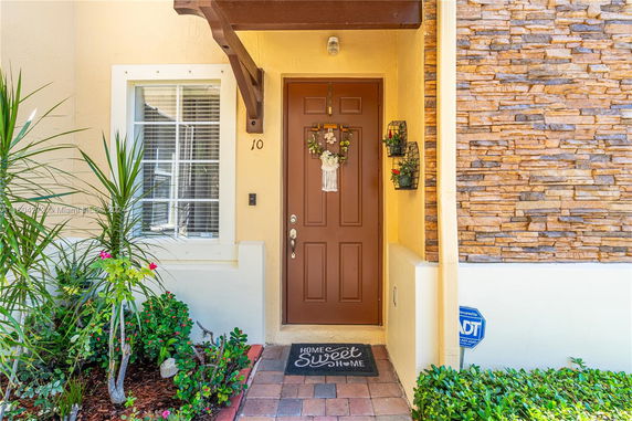 Front view of a house entrance with a brown door and decorative stone facade.