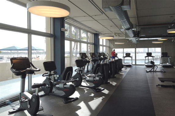 Gym area with exercise equipment and large windows.