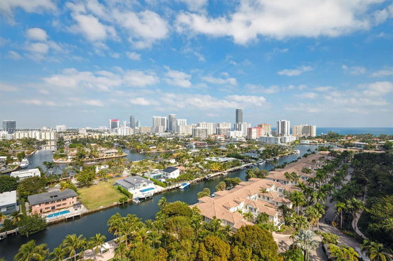 Panoramic view of a cityscape with waterways, residential areas, and high-rise buildings in the distance.