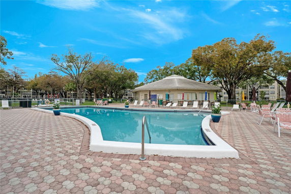 Outdoor swimming pool with surrounding patio and chairs.