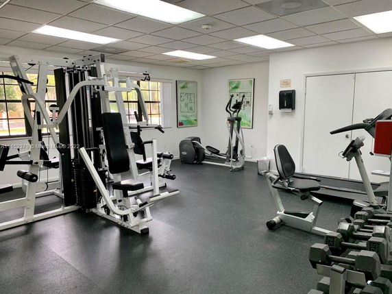 Interior view of a gym with exercise equipment including weight machines, exercise bikes, and a treadmill.