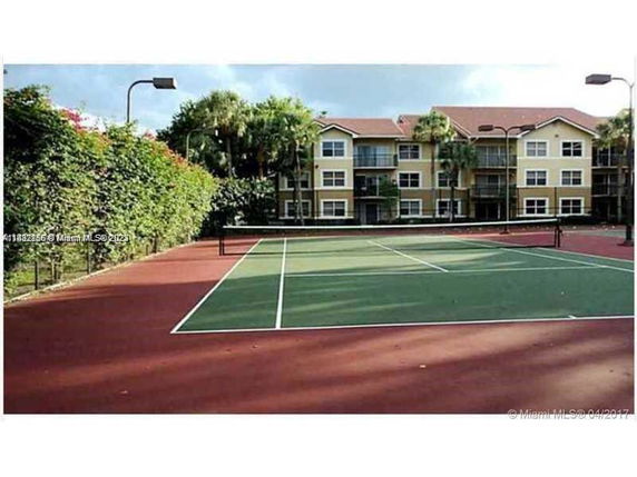Tennis court in front of a mid-rise apartment building.