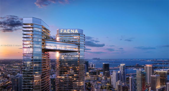 Panoramic view of a modern skyscraper with a connecting bridge and surrounding cityscape at sunset.