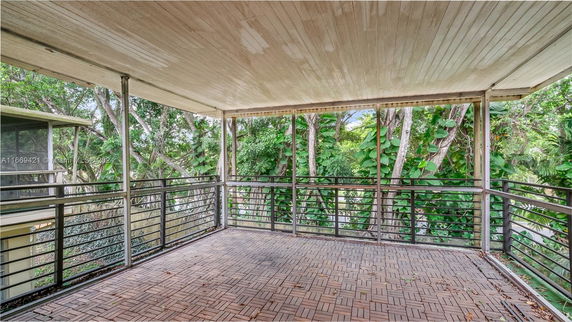 Covered rooftop area with railing and wooden tiled flooring.